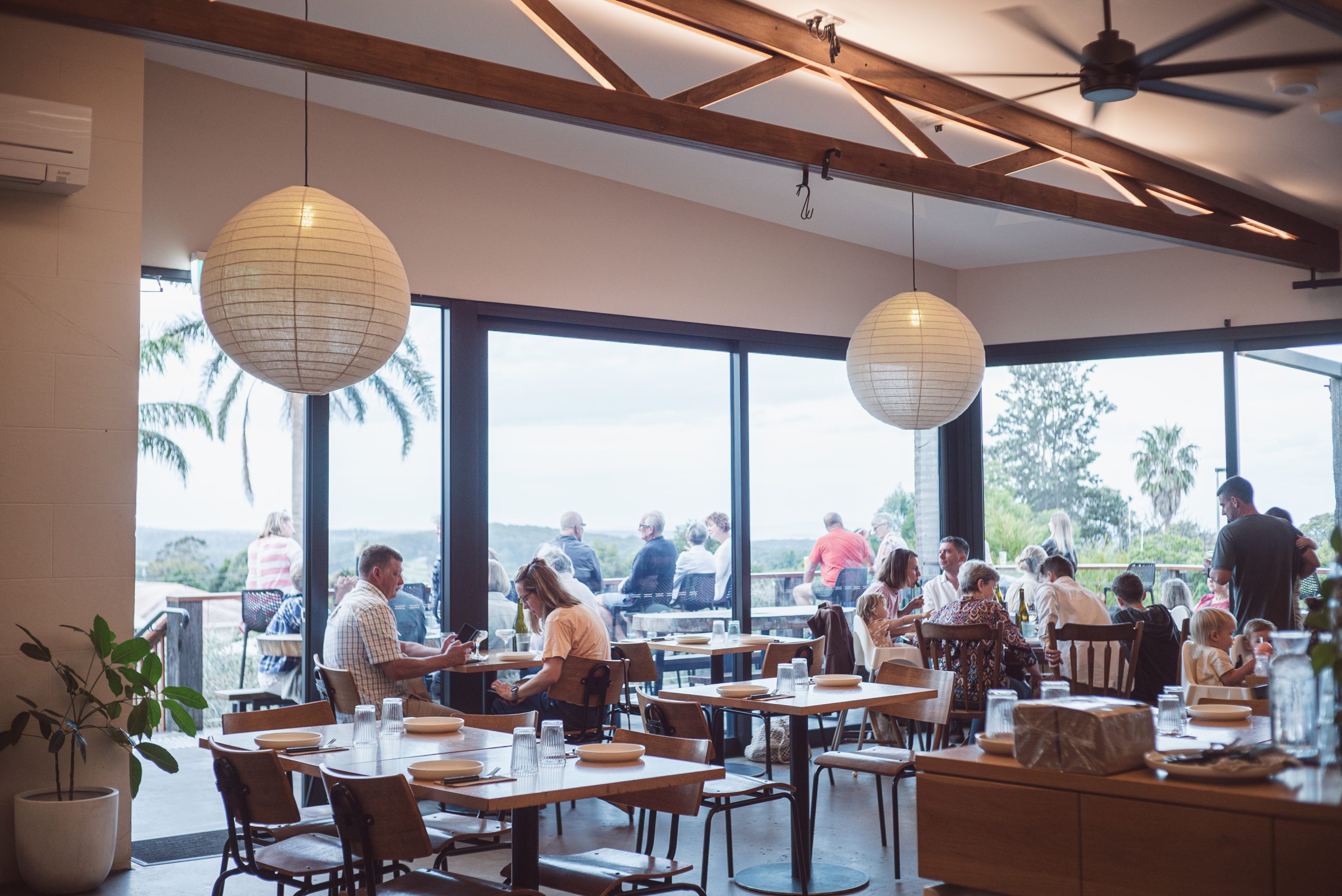 A seating area in a resturant. Large open windows letting in natural light. Bright inside.